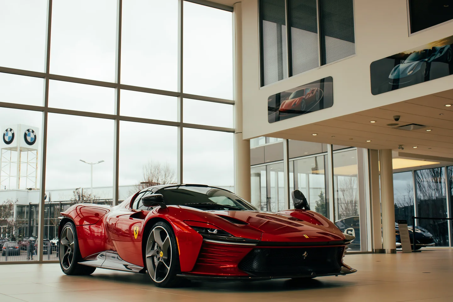 A red Ferrari Daytona SP3 three-quarter view with the full height of the showroom glass behind it.